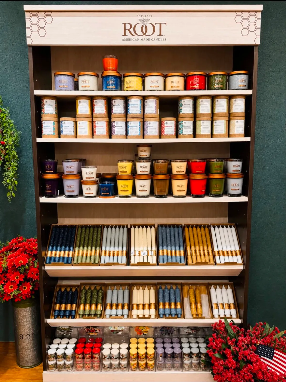 A tall shelf of Root jar candles and dinner tapers in rows of color
