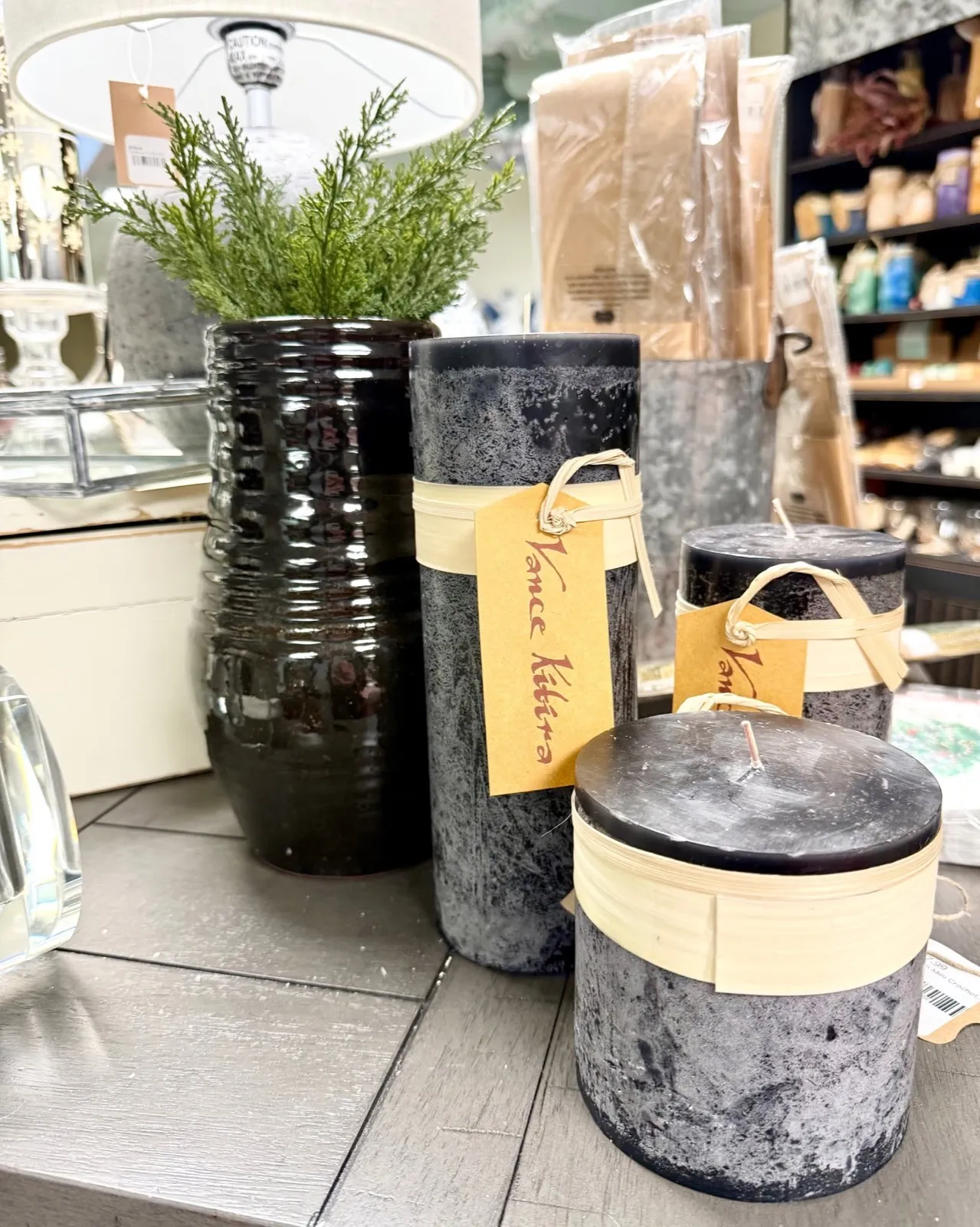 Charcoal pillar candles of different heights beside a black ribbed ceramic vase