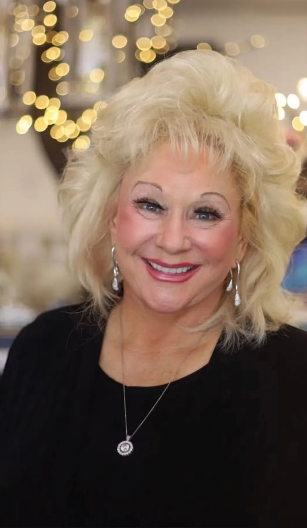 Shary Duff, smiling, with gold lights sparkling behind her