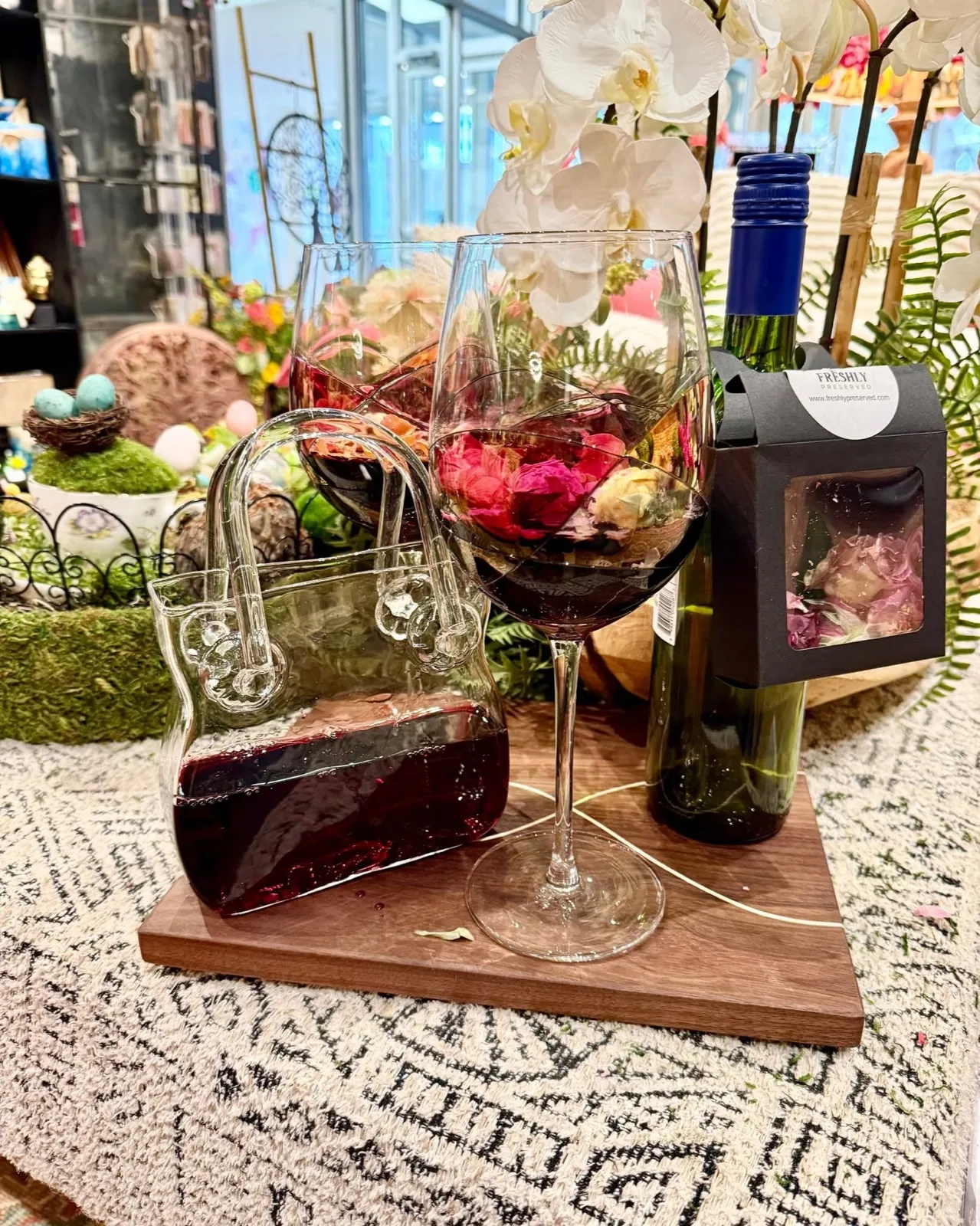 A glass of red wine and a bottle on a walnut board